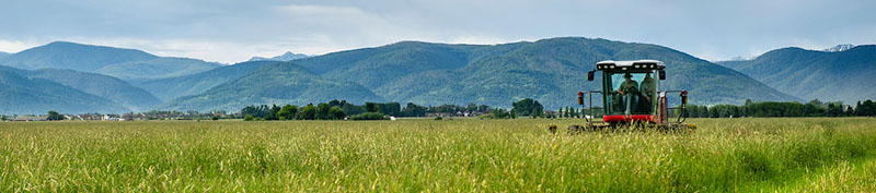 Tractor in farm field in front of mountains